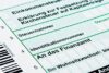 Eine Nahaufnahme eines deutschen Steuerformulars mit hervorgehobenen Abschnitten für Einkommen, Kirchensteuer, Steuernummer, Identifikationsnummer und der Adressierung an das Finanzamt für Humanressourcen.