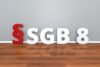 3D-Buchstaben und eine Zahl stehen aufrecht auf einem Hartholzboden vor einer grauen Wand und ergeben das Bild „$sgb8“.