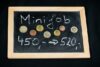 Eine Kreidetafel mit der Aufschrift „Minijob“ zeigt eine Lohnerhöhung von 450 auf 520 Euro an. Darüber ist eine Sammlung von Euromünzen zu sehen, die ein Einkommen bzw. Gehalt symbolisieren.