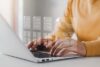 Eine Person in einem gelben Pullover organisiert effizient digitale Dokumente auf einem Laptop, mit einer grafischen Überlagerung von Dateisymbolen und Häkchen, die Aufgabenverwaltung und Produktivität im Personalmanagement symbolisieren.