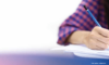 Eine Person in einem gemusterten Hemd schreibt mit einem blauen Stift Notizen auf ein weißes Blatt Papier mit weichem Hintergrund.