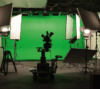 Ein professionelles Videoproduktions-Setup mit einer Kamera auf einem Stativ, Beleuchtungsgeräten und einem Greenscreen-Hintergrund für Chroma-Key-Effekte, verwaltet von einem erfahrenen Personalmanagement-Team.