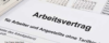 Nahaufnahme eines deutschen Arbeitsvertrags mit Taschenrechner und Brille im Hintergrund, die die Dokumentation und Vorbereitung von Humanressourcen hervorhebt.