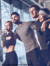 Eine Gruppe von vier jungen Erwachsenen posiert fröhlich zusammen in einem Fitnessstudio und zeigt einen Moment der Freundschaft und Fitness.