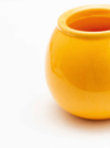 Leuchtend gelber Keramiktopf auf weißem Hintergrund.