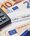 Finanzielle Berechnung anhand einer deutschen Gehaltsabrechnung mit Euro-Währung und einem Taschenrechner, der eine Gehaltsabrechnung oder Budgetplanung suggeriert.