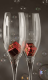 Zwei leere Champagnergläser enthalten kleine rote Geschenkschachteln. Der Hintergrund ist dunkel mit verstreuten Blasen, was eine festliche, feierliche Atmosphäre schafft.