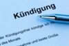 Nahaufnahme eines Dokuments mit dem deutschen Wort „Kündigung“ oben, ein Stift liegt diagonal über dem Papier. Im Hintergrund ist ein Teil des Textes sichtbar.