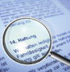 Eine Lupe vergrößert den deutschen Text „14. Haftung“, wobei der weitere umgebende Text sichtbar, aber verschwommen ist. Das Dokument scheint eine formelle rechtliche oder vertragliche Vereinbarung zu sein.