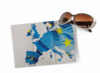 Eine Sonnenbrille liegt über einem gefalteten Papier mit einer Europakarte, die über der Flagge der Europäischen Union mit blauem Hintergrund und gelben Sternen liegt.