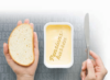 Eine Hand hält links eine Scheibe Brot, die andere Hand rechts ein Messer und schwebt über einem Butterbehälter. Auf der Oberfläche der Butter steht das Wort „Pensionskassen“.