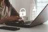 Person tippt auf einem Laptop, während Symbole für Datenschutz und Datensicherheit, wie ein Schloss und ein Passwortfeld, auf dem Bildschirm erscheinen. Symbolisiert den Schutz von Beschäftigtendaten und die Bedeutung von Sicherheit bei der Dateneingabe.