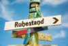 Holzwegweiser mit der Aufschrift 'Ruhestand' und einem Pfeil nach rechts, symbolisiert den Eintritt in den Ruhestand und den Beginn eines neuen Lebensabschnitts.