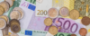 Verschiedene Stückelungen von Euro-Banknoten und Münzen sind ausgebreitet und erinnern an die Geldtransaktionen im Arbeitsrecht. Die Banknoten reichen von 5 bis 500 Euro, und die Münzen umfassen unterschiedliche Cent- und Eurowerte, sodass eine bunte Mischung europäischer Währungen zu sehen ist.