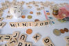 Symbolfoto Minijob: Holzbuchstaben mit dem Wort „Minijob“, daneben Euro-Münzen, Geldscheine und ein Sparschwein als Hinweis auf Entgeltabrechnung und Rentenversicherung.