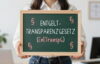 Frau hält Tafel hoch, auf der Entgelttransparenzgesetz steht