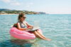 Frau arbeitet am Laptop im Schwimmring auf dem Meer