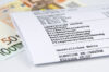 Detailansicht einer deutschen Lohnabrechnung mit Euro-Geldscheinen. Zu sehen sind die gesetzlichen Abzüge: Lohnsteuer, Solidaritätszuschlag, Kirchensteuer, Krankenversicherung, Rentenversicherung, Arbeitslosenversicherung und Pflegeversicherung. Darunter steht "Gesetzliches Netto" sowie weitere Abzüge.