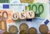 GKV-Holzwürfel auf Euro-Banknoten und Münzen veranschaulichen Finanzen und Beiträge der gesetzlichen Krankenversicherung.